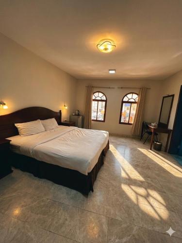 a bedroom with a large bed and two windows at Alreef Hotel Suits in Muscat