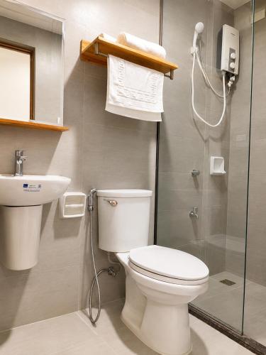 a bathroom with a toilet and a sink and a shower at Bambu Suites in Puerto Princesa City