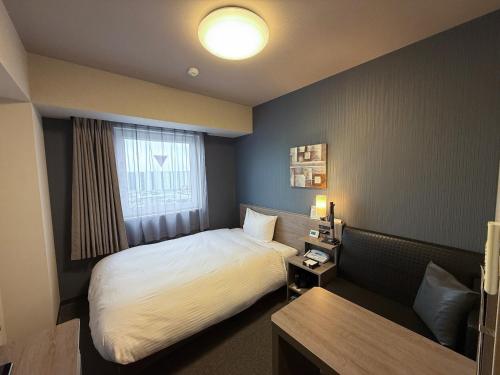 a hotel room with a bed and a window at Hotel Route-Inn Kanuma Inter in Kanuma