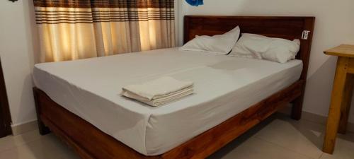a large bed with white sheets and pillows on it at RS Green Barathi in Kilinochchi