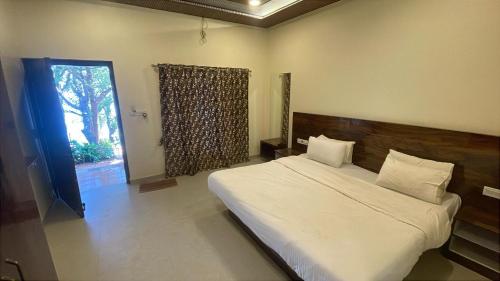a bedroom with a large white bed and a window at The Byke Retreat - Laxmi Resort - Pan India Pure Veg Hotel Chain in Matheran