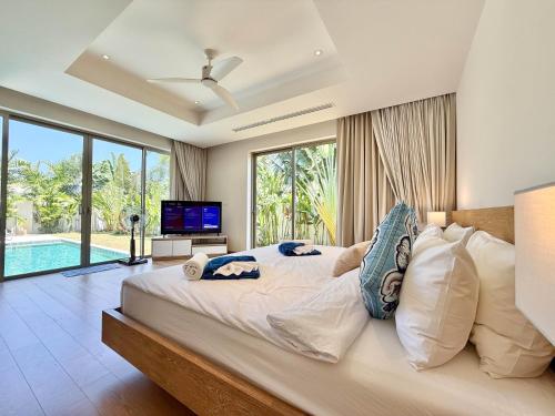 a bedroom with a large bed and a tv at Bali-Style 4 BR Private Pool Villa - Trichada in Phuket