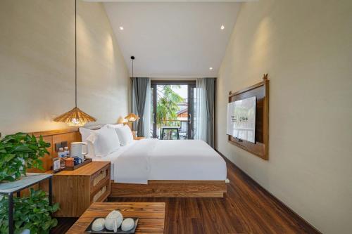 a bedroom with a bed and a desk and a window at MOUNT WELL RESORT HOTEL in Lijiang