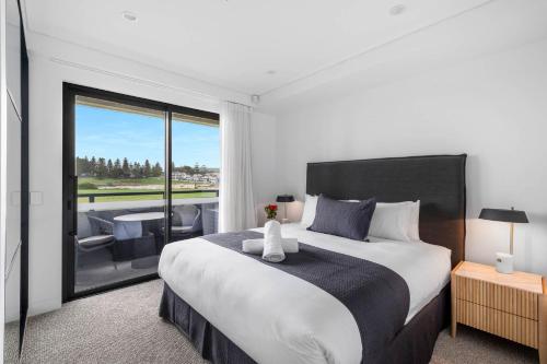 a bedroom with a large bed and a balcony at Kove Apartment - B02 in Kiama