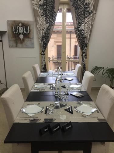 einem Esstisch mit weißen Stühlen und einem schwarzen Tisch mit Siddx sidx sidx in der Unterkunft B&B Paolo e Mariella in Palermo
