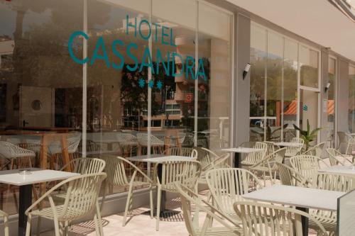 a restaurant with white tables and chairs in front of a window at Hotel Cassandra in El Arenal