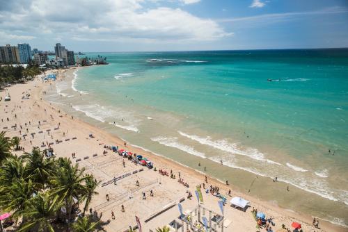 a group of people on a beach with the ocean at OCEAN VIEW DELUXE SUITE: PVT. BEACH & POOL in San Juan