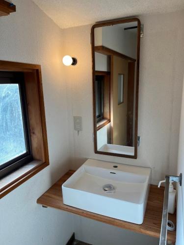 a bathroom with a white sink and a mirror at かんぬしの宿 in Yamaguchi
