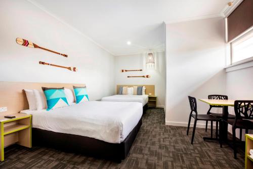 Habitación de hotel con 2 camas y mesa en Nightcap at Caringbah Hotel, en Caringbah