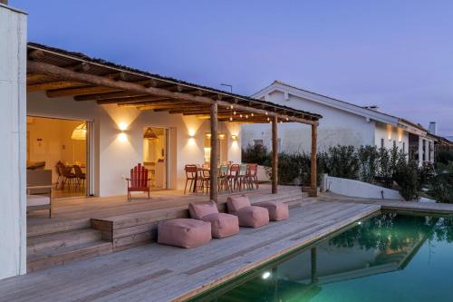 a wooden deck with a table and chairs next to a swimming pool at Casa Terracotta with Private Pool in Comporta