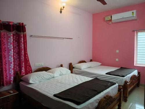 two beds in a room with pink walls at Vihaasam Homestay in Thanjāvūr