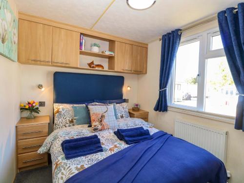 a bedroom with a blue bed with a dog sitting on it at 25 Foxburrow Hang in Great Yarmouth