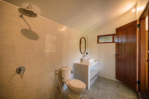 a bathroom with a toilet and a sink and a mirror at Tegal Wangi Penebel in Penebel