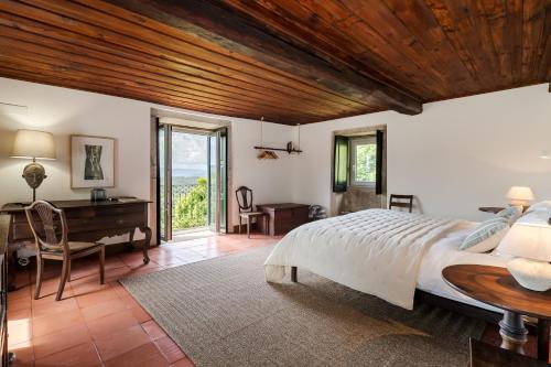 a bedroom with a large bed and a wooden ceiling at Eira Country House in Ponte de Lima