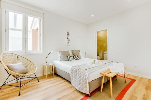 a white bedroom with a bed and a chair at Espinho Beach 4 Stays with Terrace in Espinho