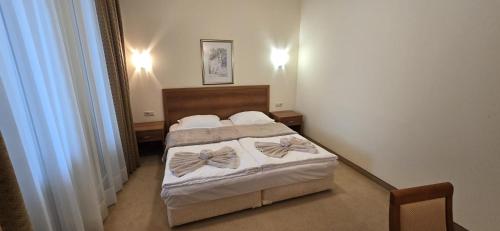 a bedroom with a bed with white sheets and bows at Apartment SunSet rezort - sea wiew in Pomorie