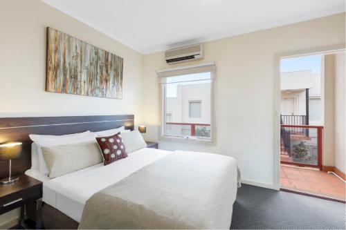 um quarto com uma grande cama branca e uma janela em Hawthorn Gardens Serviced Apartments em Melbourne