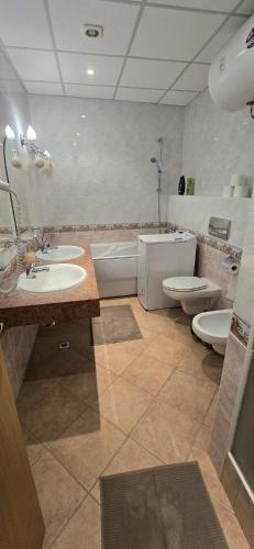 a bathroom with two sinks and a tub and a toilet at Apartment SunSet rezort - sea wiew in Pomorie