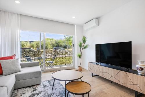 a living room with a tv and a couch and a table at Sunny Stays Espinho | Balcony & Pool in Espinho