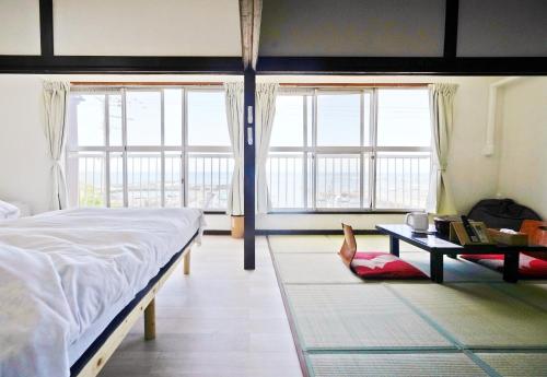 a bedroom with a bed and a table and windows at 海凪旅館 in Tateyama
