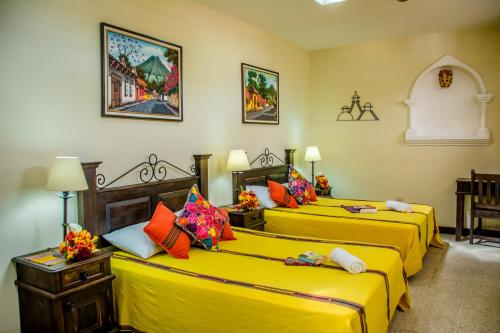 three beds in a room with yellow sheets at Posada San Vicente by AHS in Antigua Guatemala