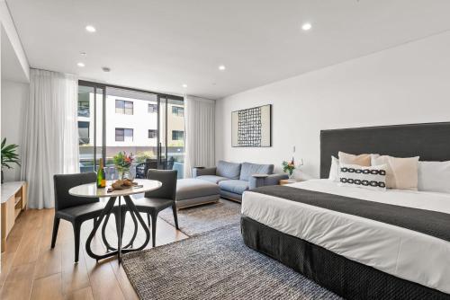 a bedroom with a large bed and a living room at Kove Apartment - G02 in Kiama