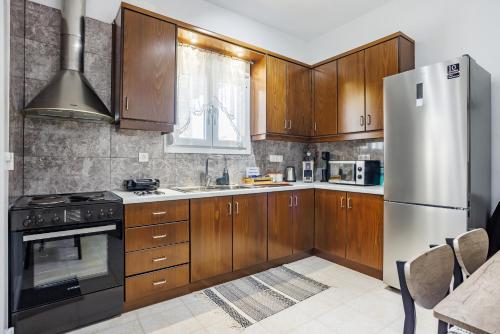 a kitchen with wooden cabinets and a stainless steel refrigerator at Dimitra's House in Glossa