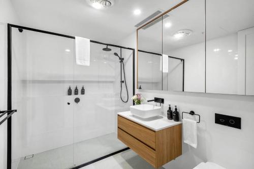 a white bathroom with a sink and a shower at Kove Apartment - G02 in Kiama