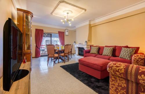 a living room with a red couch and a table at Cantinho em Cascais, Spacious 3BR with Balconies in Cascais