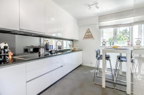 a white kitchen with white cabinets and a table at Luxury Beach Experience in Lisbon in Oeiras