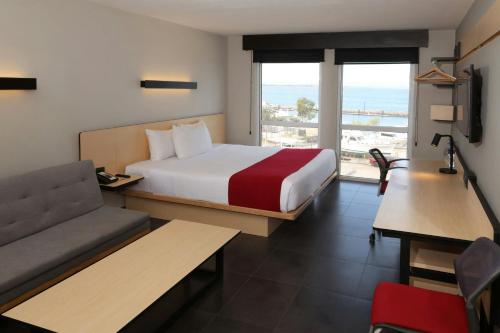 a hotel room with a bed and a couch and a window at City Express by Marriott La Paz in La Paz