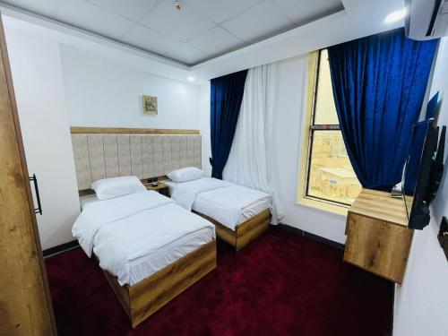 a hotel room with two beds and a window at Danzha Hotel 1 in Erbil