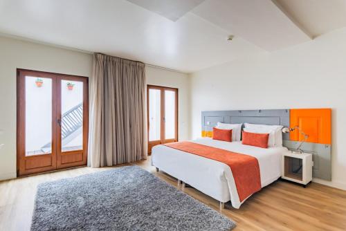 a bedroom with a large bed and a large window at Porta da Arrábida Suites in Palmela