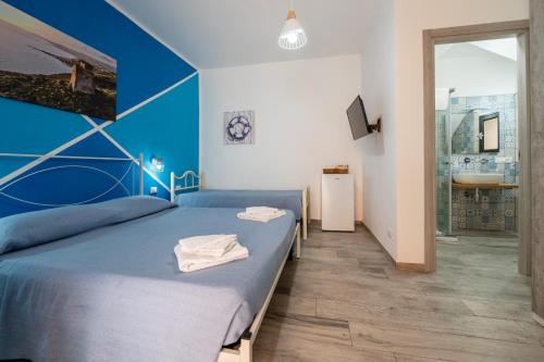 a bedroom with two beds and a bathroom with a sink at Perla Marina Rooms in Realmonte