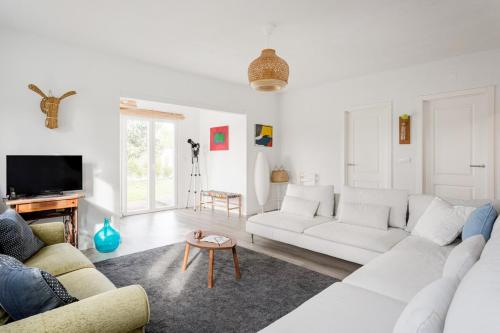 a white living room with a white couch and a table at Pinhal da Praia em Melides in Quinta da Cascalheirinha