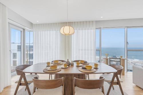 a dining room with a table and chairs with a view of the ocean at Sal D’Ouro Skyline & Sea Views in Canidelo
