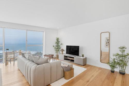 a white living room with a couch and a television at Sal D’Ouro Skyline & Sea Views in Canidelo