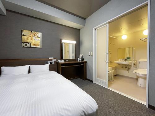 a bedroom with a bed and a bathroom with a toilet at Hotel Route-Inn Ina Inter in Minamiminowa