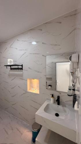 a white bathroom with a sink and a mirror at Reef ALjabal Rest in Minthār