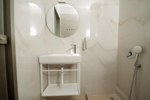 a white bathroom with a sink and a mirror at White Nest Rooms in Potos