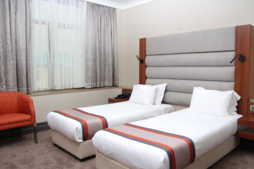 a hotel room with two beds and a chair at Batumi World Palace in Batumi