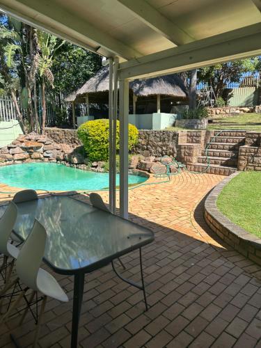 a patio with a table and chairs next to a swimming pool at Royaltics place in Weltevredenpark