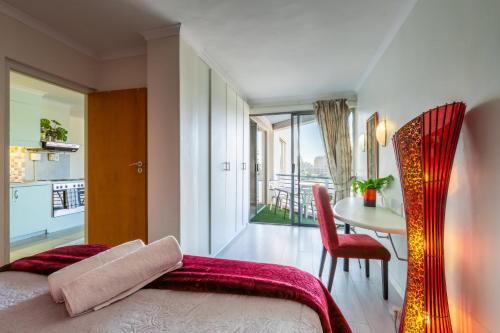 a bedroom with a bed and a table with a view at 419 Ocean Breeze in Cape Town
