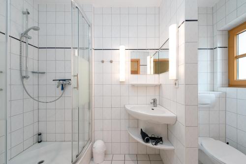 a white bathroom with a sink and a shower at Höfthus 8 - Bade- & Saunawelt täglich inklusive in Alt Reddevitz