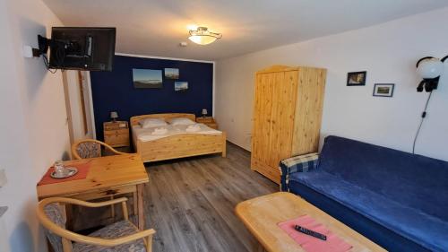 a living room with a blue couch and a bed at Ratskeller Geising in Geising
