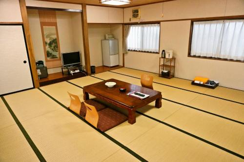 a living room with a table and chairs in it at Shugyoku no Yu Yakushido Onsen in Oshu