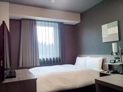 a hotel room with a bed and a window at Hotel Route-Inn Nihonmatsu -Kokudo 4Gou- in Nihommatsu