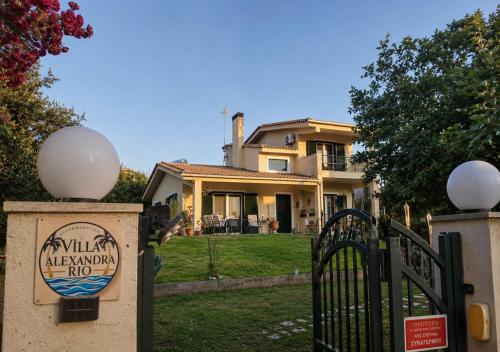 a house with a sign in front of a gate at Villa Alexandra Rio Patra in Áyios Vasílios