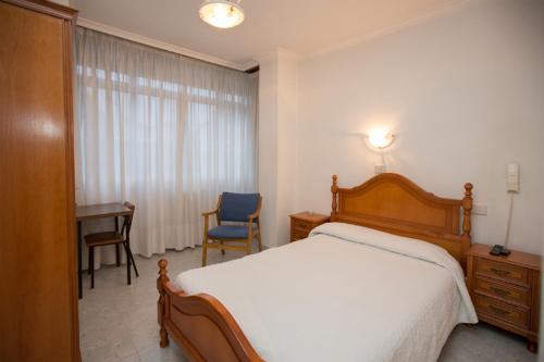 1 dormitorio con cama, escritorio y ventana en Hotel Venezuela, en Vilalba