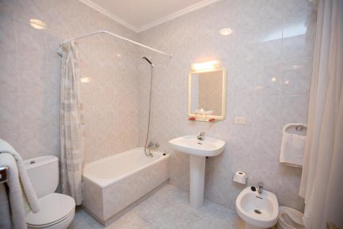 een badkamer met een wastafel, een toilet en een bad bij Hotel Venezuela in Villalba